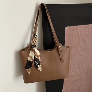 Detail of brown tote bag with contrast stitching and floral silk scarf on handle