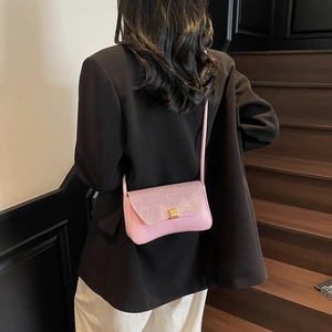 Sac bandoulière rose à paillettes pour femme avec fermoir doré porté par un mannequin
