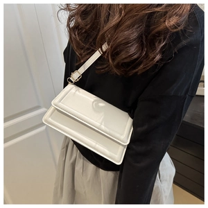 Close-up of a white rectangular crossbody bag with decorative stitching and gold buckle