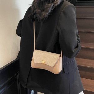 Sac bandoulière beige élégant avec rabat pailleté et boucle dorée sur modèle