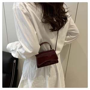 Rear view of a burgundy patent leather mini crossbody bag styled for summer wear