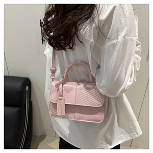 Gros plan du sac bandoulière rose clair avec texture tressée et étiquette décorative