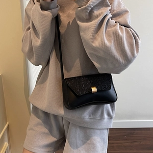 Petit sac carré noir à rabat pailleté avec boucle dorée porté par un mannequin