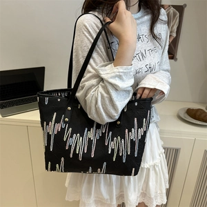Black canvas tote bag with colorful wave embroidery and leather straps in a casual office setting