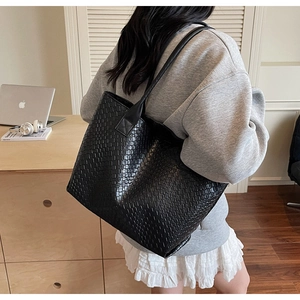 Détail du sac cabas en cuir tressé noir montrant la texture quadrillée et les bandoulières