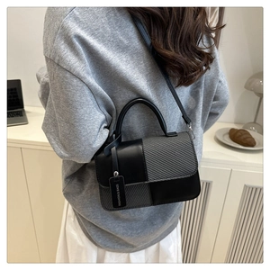Détail du sac bandoulière bicolore avec texture tissée grise et finition cuir noir