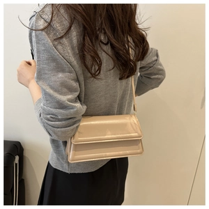 Detail of beige square crossbody bag featuring quilted flap edges and matte leather texture