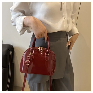 Deep burgundy shell bag featuring glossy patent leather and gold zipper details
