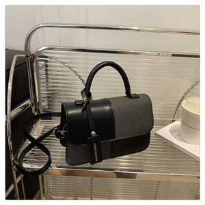 Détail d'un sac bandoulière chic avec texture tissée grise et finitions en cuir noir