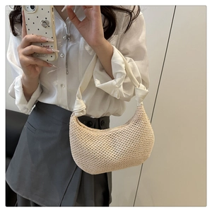 Close-up detail of beige woven straw moon bag with stylish white knotted strap handle