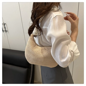 Close-up of beige woven crescent bag with knot detail on the shoulder strap