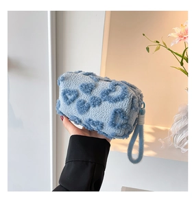 Detail of blue plush handbag with heart texture and thick handle rope held by model