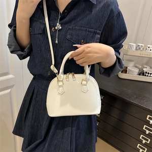 Minimalist white patent leather shell bag with adjustable shoulder strap and gold hardware