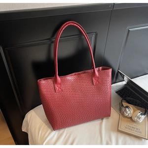 Gros plan sur un grand sac cabas rouge avec une texture tissée et un style chic