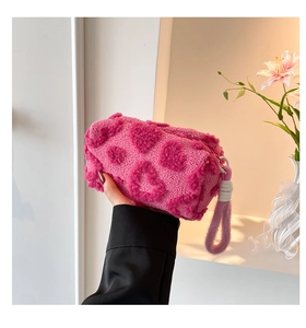 Detailed view of pink plush handbag with heart patterns and soft fleece texture