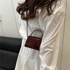 Minimalist burgundy patent leather crossbody bag with top handle and glossy finish