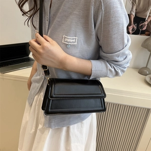 Minimalist black leather square crossbody bag with gold hardware for women in daily scene
