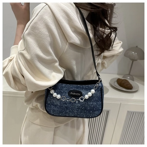 Detail of floral denim shoulder bag with pearl chain and fashion tag on a model