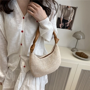 Stylish hand-woven beige straw underarm bag with dark brown leather handle for beach vacations