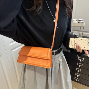 Chic orange rectangular crossbody bag with fine stitching shown in a lifestyle setting