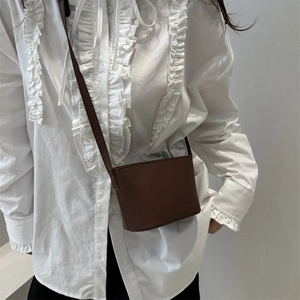 Minimalistische dunkelbraune Umhängetasche an einem Model für einen stilvollen Look