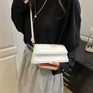 Minimalist white leather crossbody bag with geometric flap detail for women on model