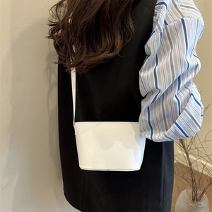 Weiße Bucket-Bag aus Leder mit FANYISSA-Prägung, an Model mit Schultergurt gezeigt
