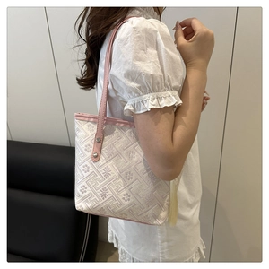 Detail of embroidered tote bag with pink leather trim and geometric pattern on model