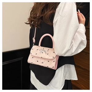Détail du sac rose avec nœud, montrant le tissu texturé et la boucle en métal argenté