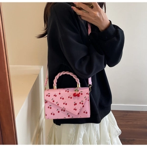 Mirror selfie showing a pink cherry pattern crossbody bag with a braided handle