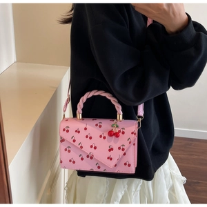 Detail of pink crossbody bag featuring cherry prints and 3D cherry charm accessory