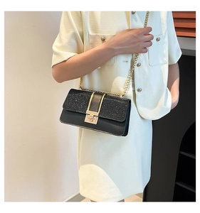 Detail of crossbody chain bag showing black sequin texture and golden metal buckle