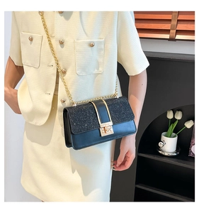 Detail of a chic black crossbody bag with sequin拼接 and gold chain strap on a model