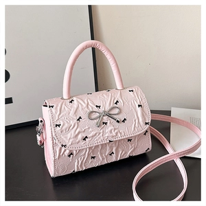 Vue détaillée du sac à main rose avec nœud papillon, texture plissée et accents argentés