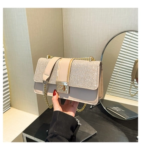Detail of beige leather and sequin crossbody bag with gold metal chain and push-lock