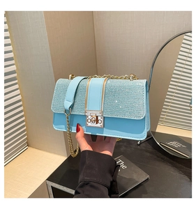 Close-up of light blue chain bag with sparkling glitter flap and gold metal lock
