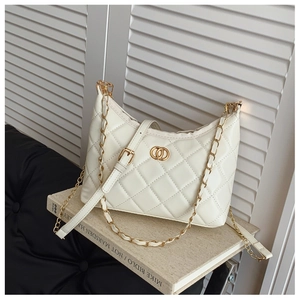 Détail d'un sac bandoulière matelassé blanc avec ferrures dorées et chaîne élégante