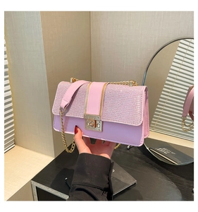 Detail of pink glitter crossbody bag with gold twist lock and metal chain strap