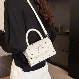 Sac bandoulière en cuir blanc avec broderies nœuds noirs et fermoir métallique argenté
