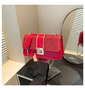 Detail of a red sequin flap bag with gold chain strap and metal square twist lock