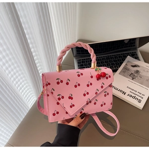 Detail of pink cherry print handbag with woven handle and cherry shaped charm decoration