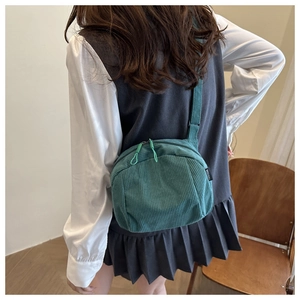 Détail d'un sac bandoulière en velours côtelé vert foncé avec texture et double zip