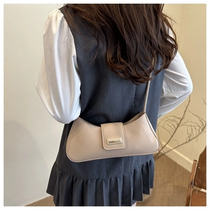 Elegant beige baguette shoulder bag worn by model, showing size and minimalist style
