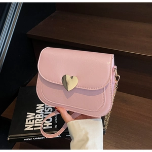 Detail of pink PU leather crossbody bag with heart-shaped golden buckle and chain strap