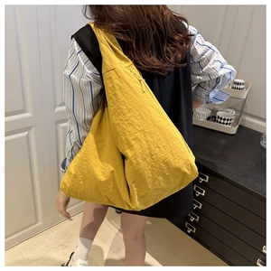 Detail of yellow crescent shoulder bag with drawstring and wrinkled nylon texture