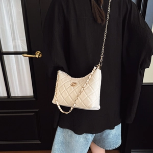 Sac bandoulière blanc matelassé avec chaîne dorée porté par un mannequin élégant