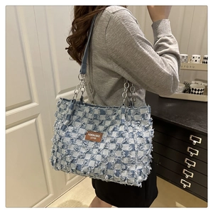 Detail of blue and white checkered tote bag with fringe texture and metal chain strap