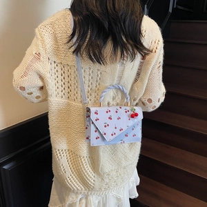 Sweet light blue handbag with cherry print and woven handle shown on model shoulder
