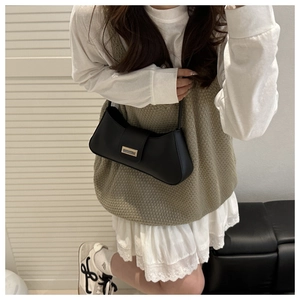 Detail of black matte leather shoulder bag with silver buckle worn on a shoulder