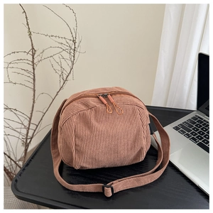 Détail d'un sac bandoulière en velours côtelé marron chaud avec double fermeture éclair
